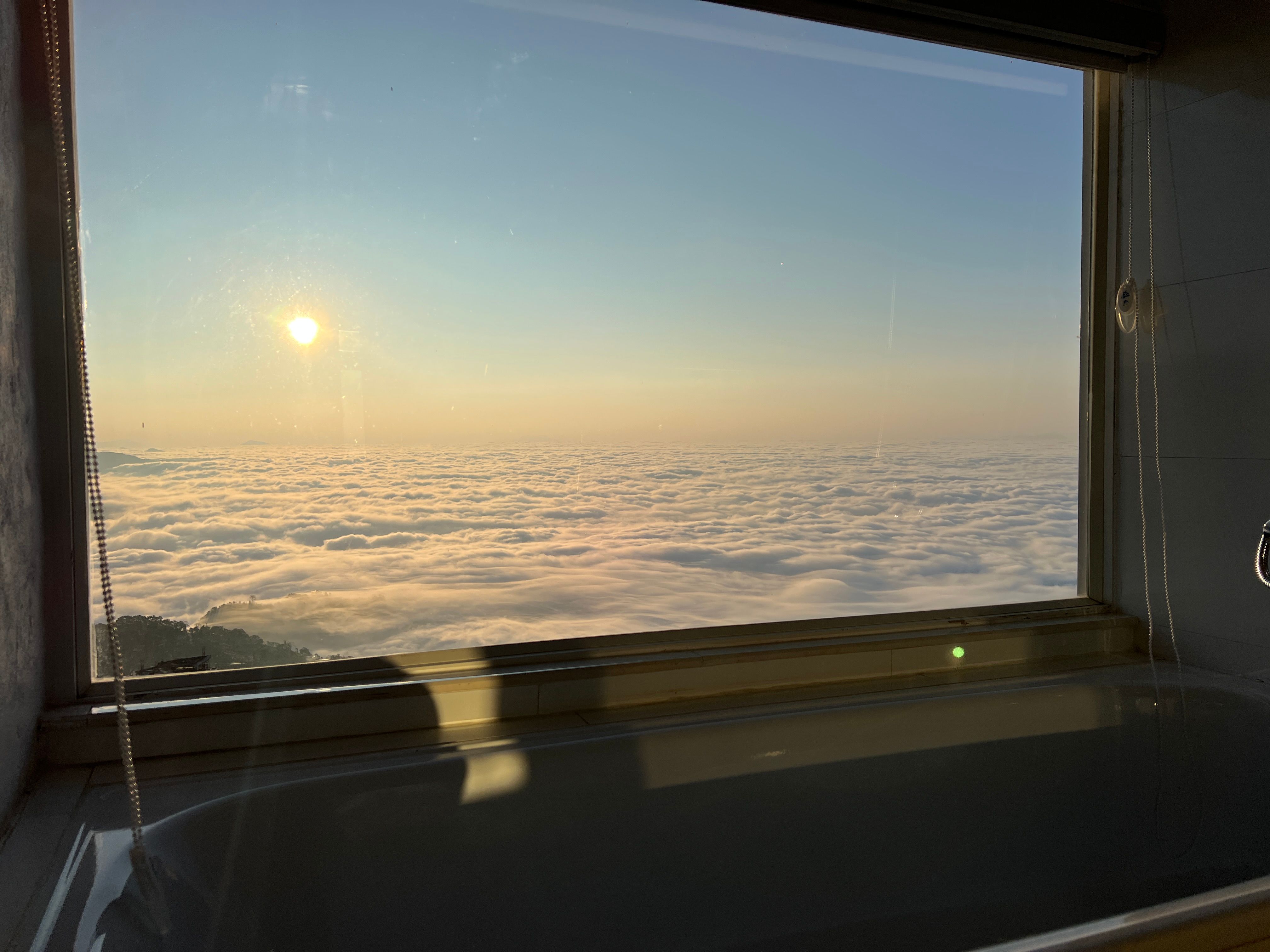 The sun over a sea of clouds, seen from the apartment's bathtub