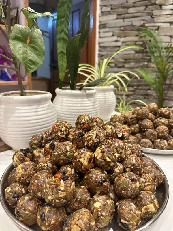 A tray piled with round dates and nuts bites, with seeds and nuts showing