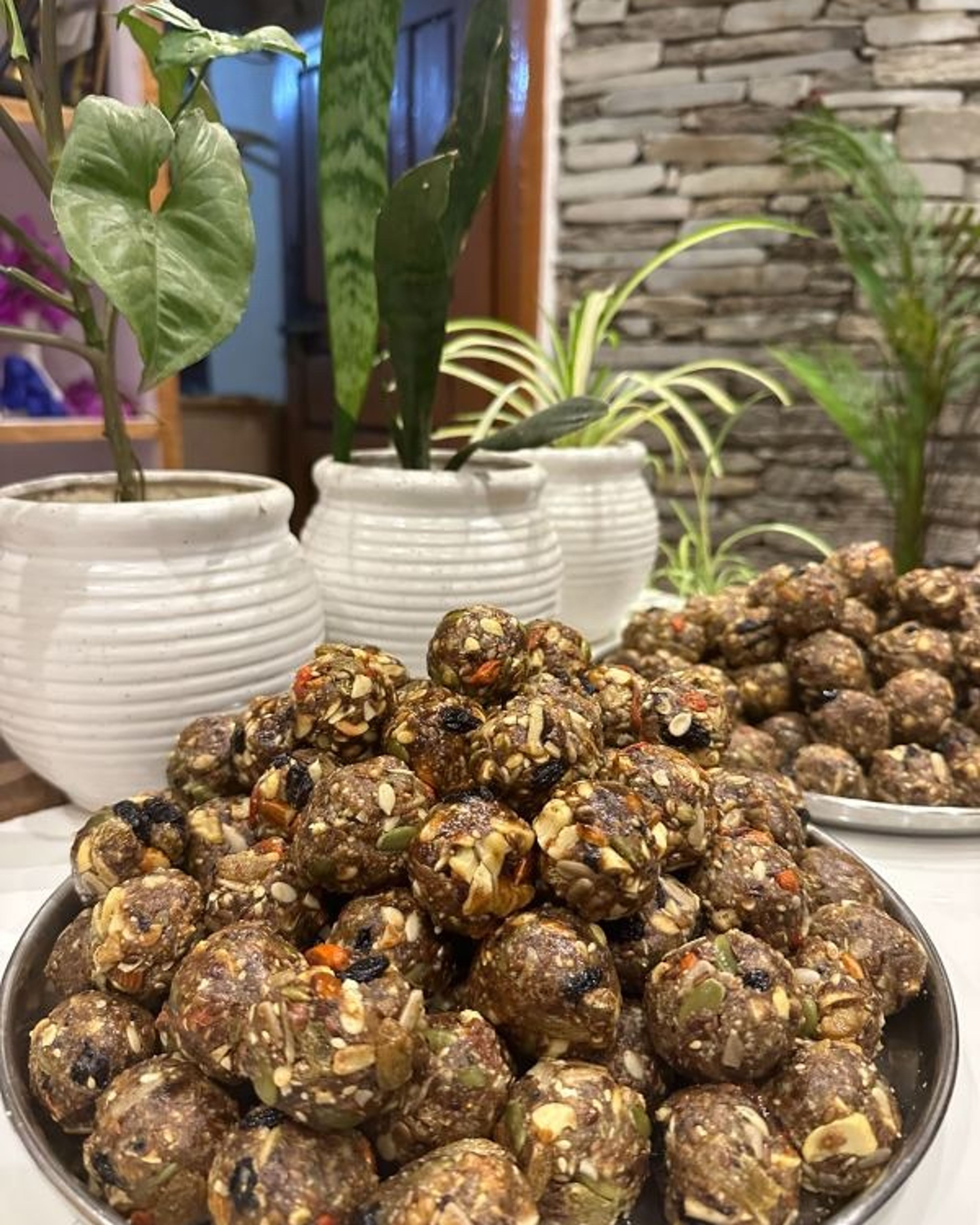 A tray piled with round dates and nuts bites, with seeds and nuts showing