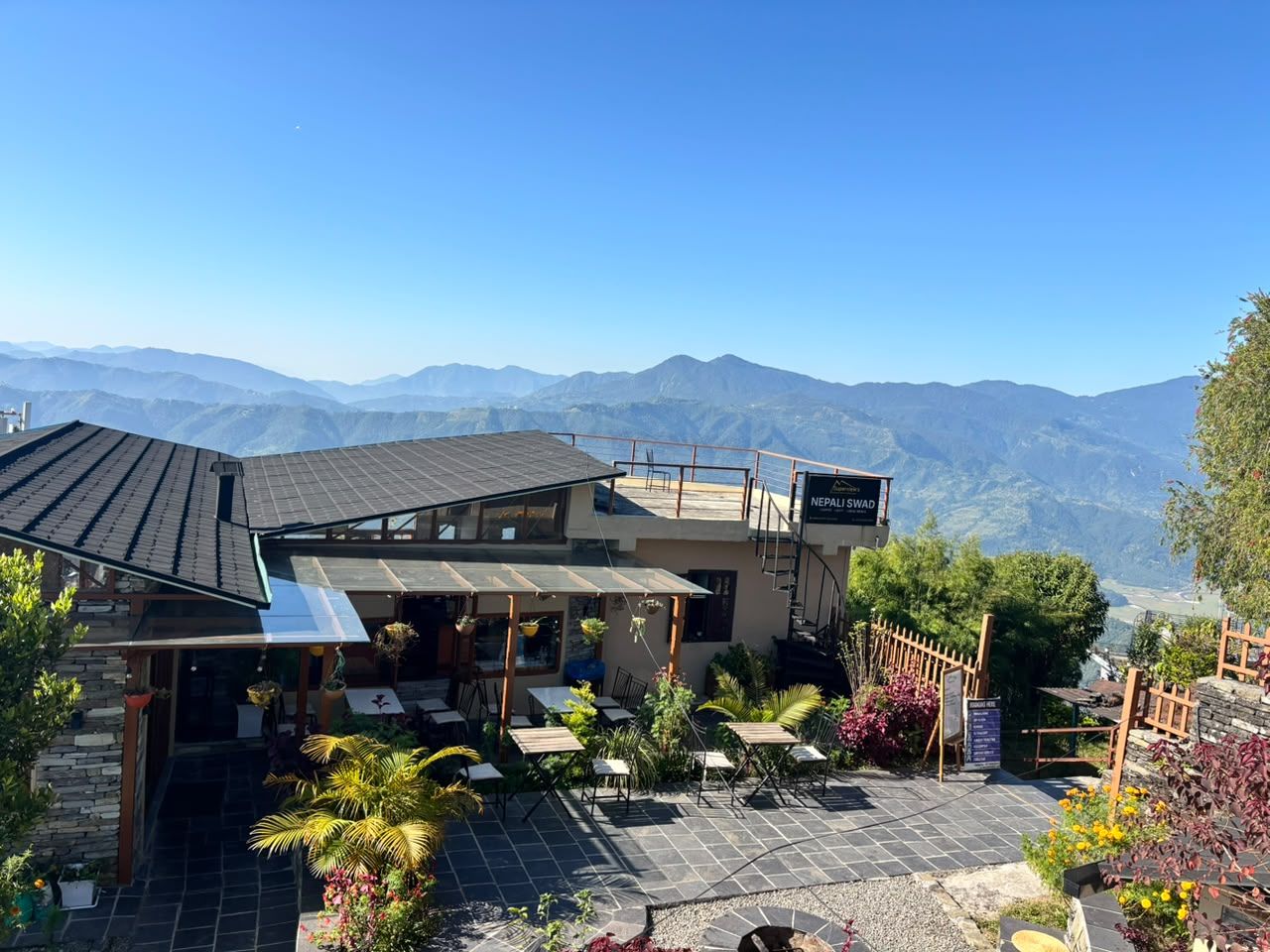 The garden café terrace with tables and the hills beyond