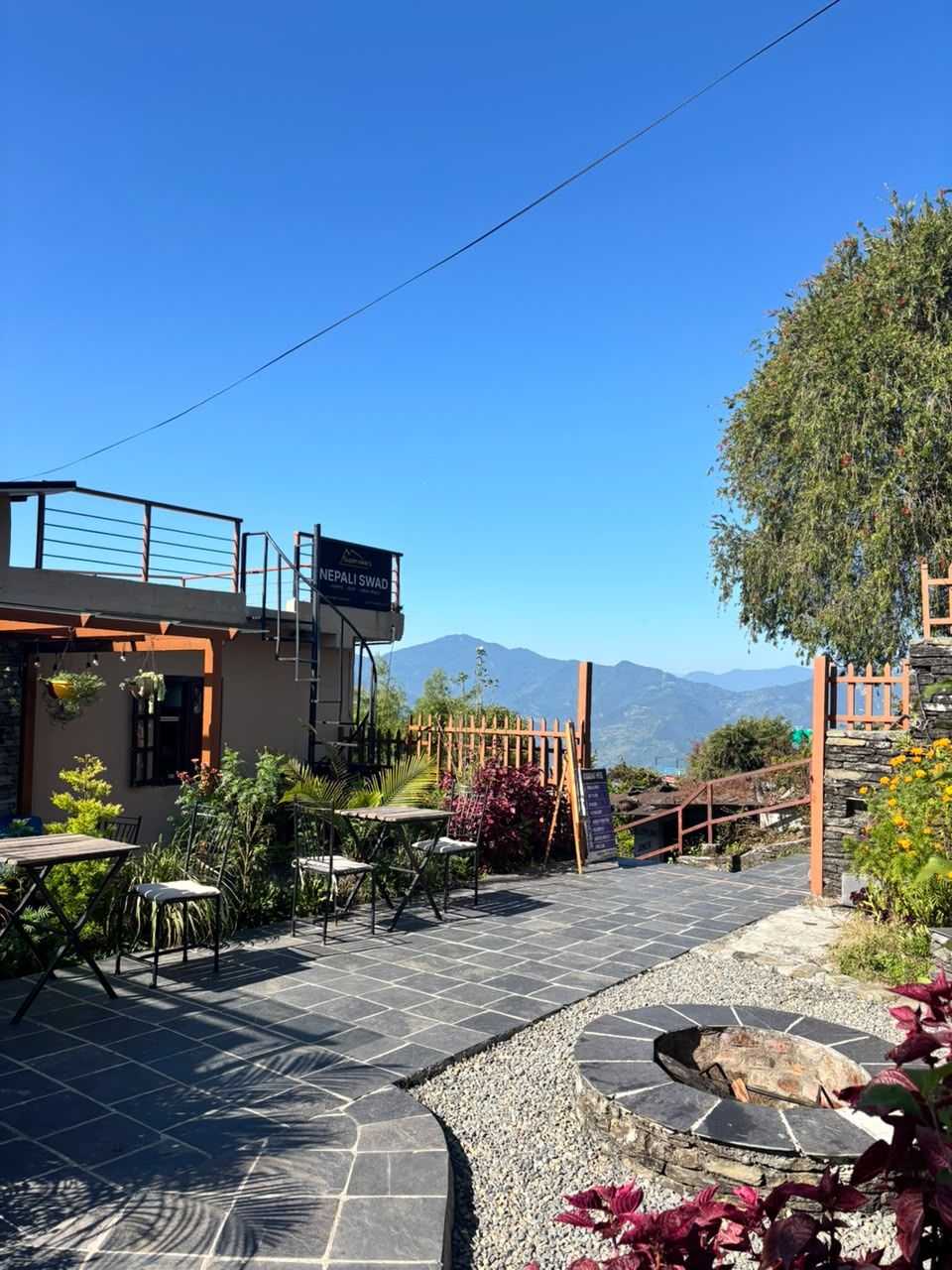 Café tables on the stone terrace next to the fire pit