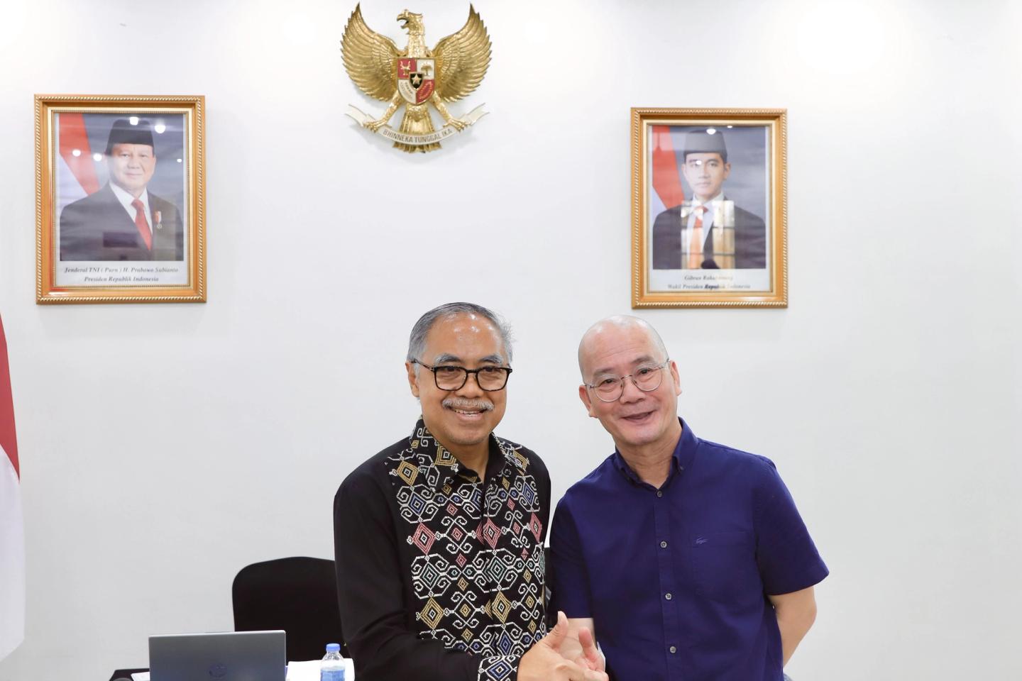 Hai đại diện chụp ảnh lưu niệm dưới quốc huy Indonesia tại sự kiện