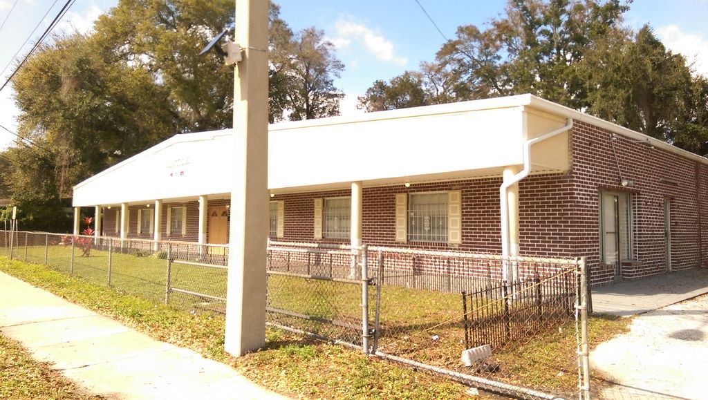 Wide view of the building before the re-roof, with the original plain cream fascia and no matching gutter trim.