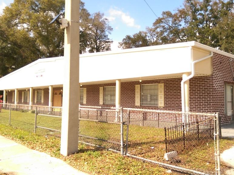 Wide view of the building before the re-roof, with the original plain cream fascia and no matching gutter trim.