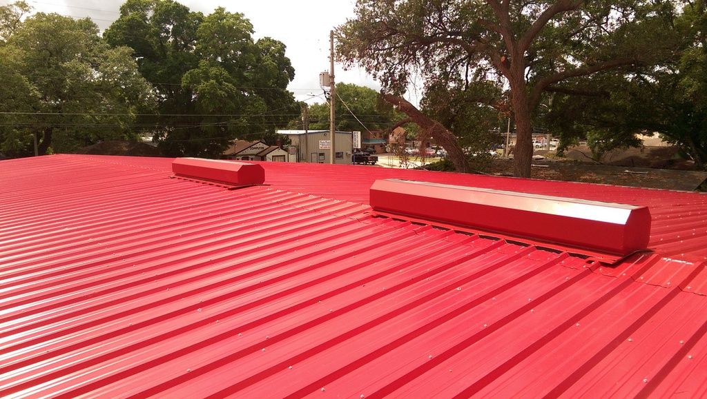 New red standing-seam metal roof with two new ridge vents installed for attic airflow.