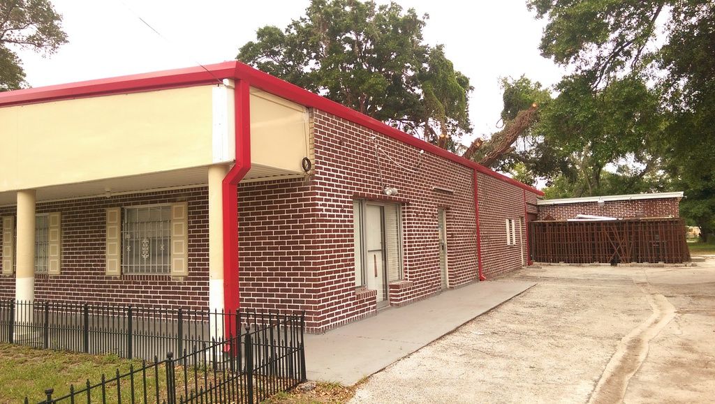 Wide view of the building after the re-roof, with a new red roofline edge and matching red gutter trim.