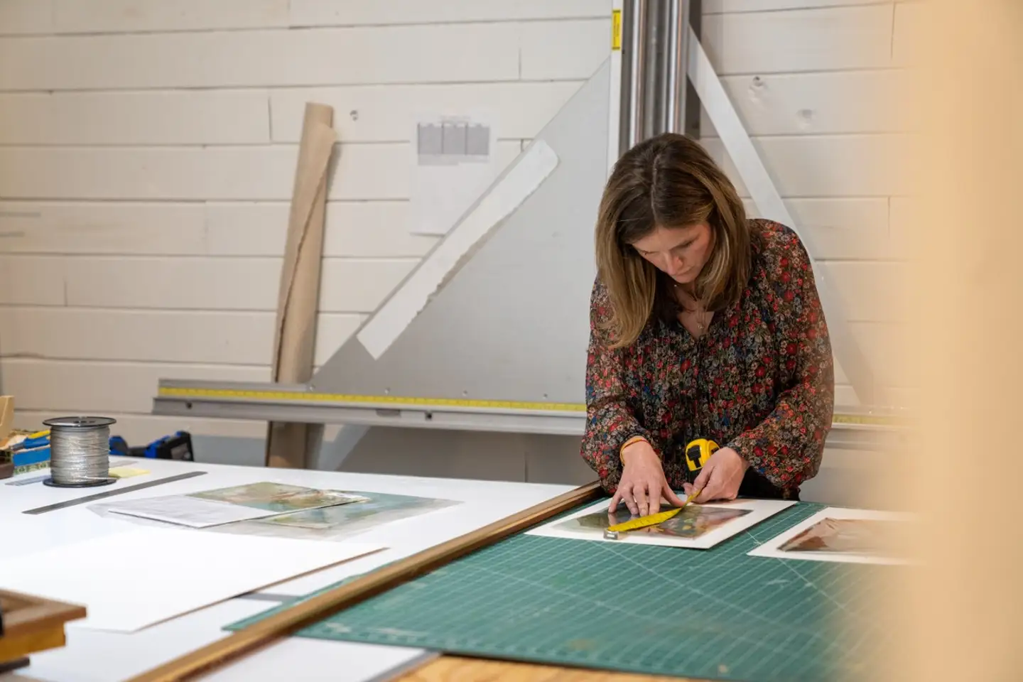 Frame House co-founder Lily Trest measuring a piece of art for framing