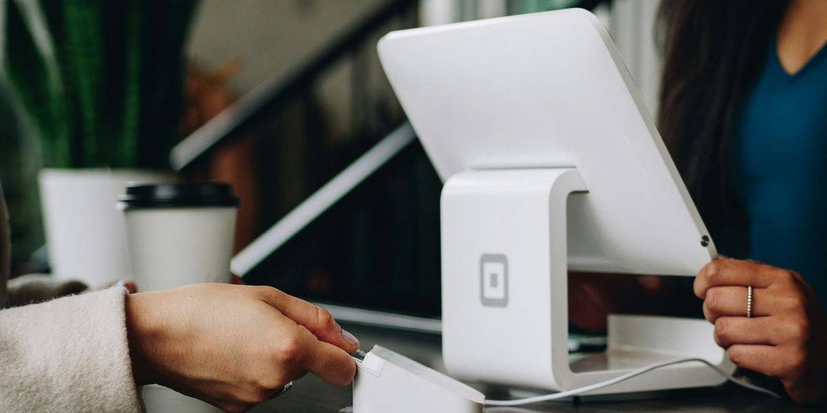 A customer tapping a card on a reader beside a tablet till on a small shop counter, an early step when you digitize a small business in Indonesia