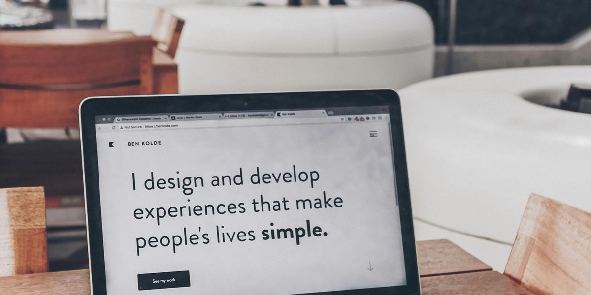 Laptop di atas meja kayu menampilkan halaman depan sebuah website perusahaan di browser, dipakai untuk memeriksa tanda website perusahaan perlu diperbarui