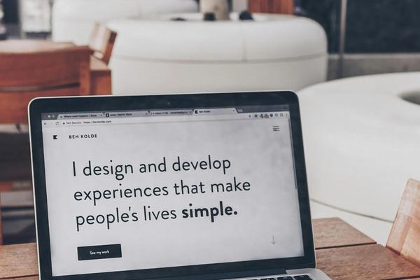 Laptop di atas meja kayu menampilkan halaman depan sebuah website perusahaan di browser, dipakai untuk memeriksa tanda website perusahaan perlu diperbarui