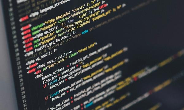 Layar monitor menampilkan kode PHP sebuah tema WordPress, gambaran pekerjaan pemeliharaan yang dihitung dalam biaya maintenance website per tahun