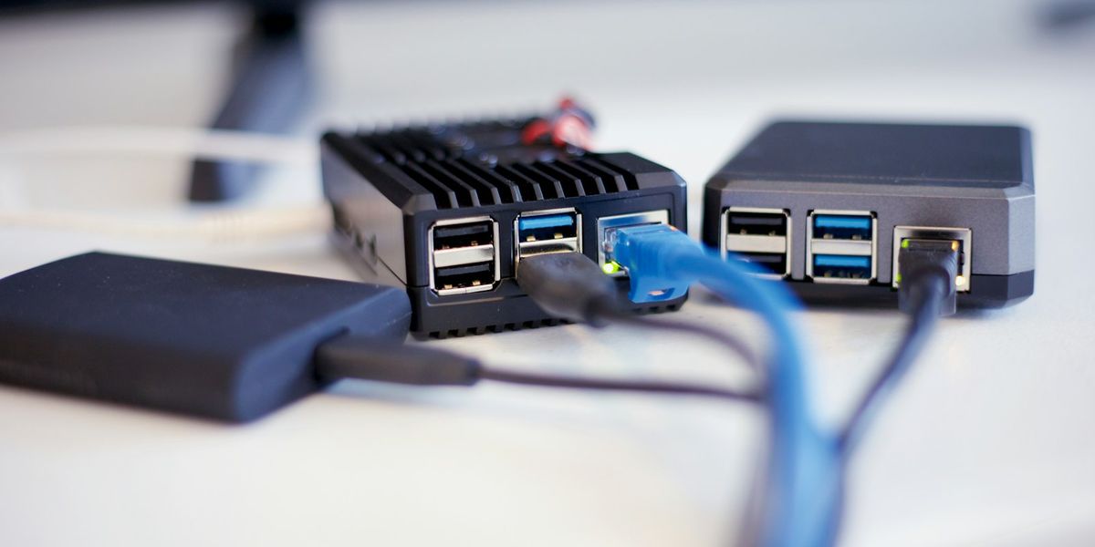 Small fanless mini-server connected to an external SSD and an ethernet cable on a white desk, a simple office backup setup