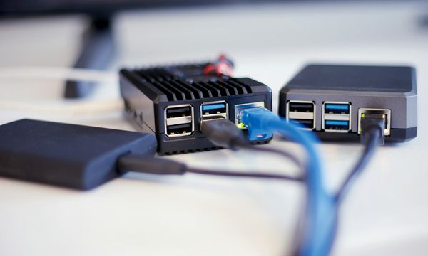 Small fanless mini-server connected to an external SSD and an ethernet cable on a white desk, a simple office backup setup