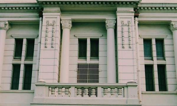White government office building with a row of columns and barred windows, where suppliers verify their LPSE registration documents