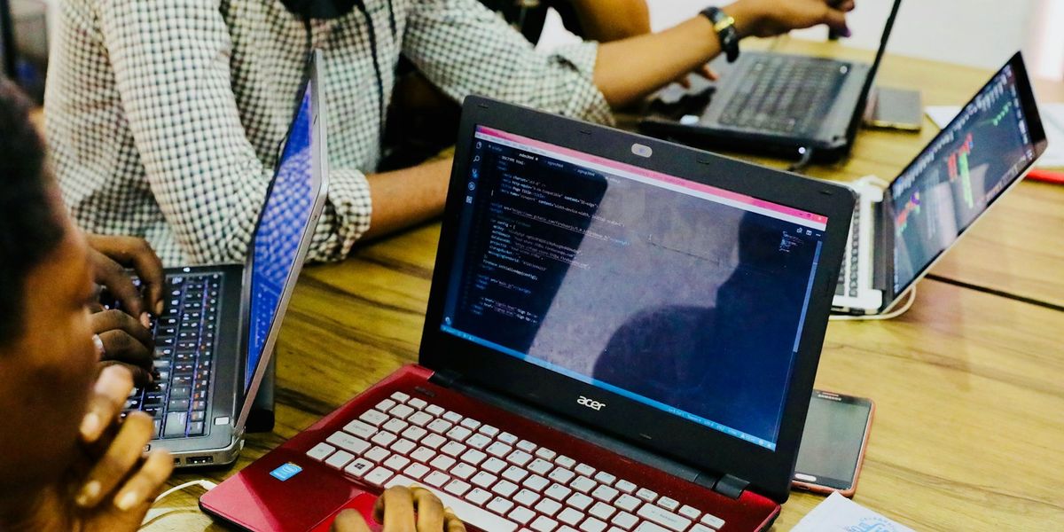 Several programmers working at one table on laptops full of code, the kind of team you assess when looking for a reliable software development company