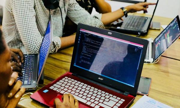 Several programmers working at one table on laptops full of code, the kind of team you assess when looking for a reliable software development company
