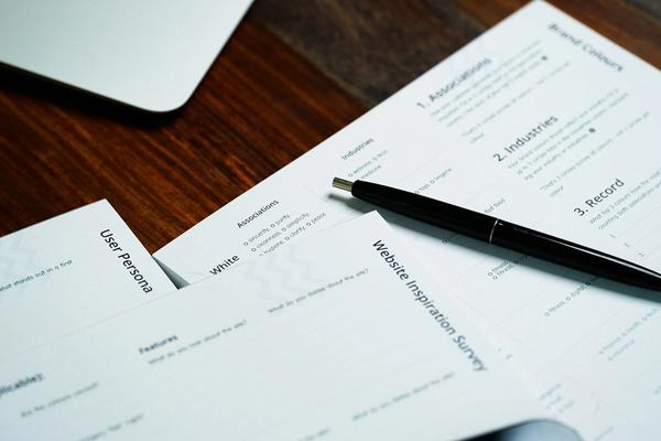 Lembar formulir pendaftaran tercetak dengan pulpen di atas meja kayu di samping laptop, gambaran pengisian data pendaftaran PSE