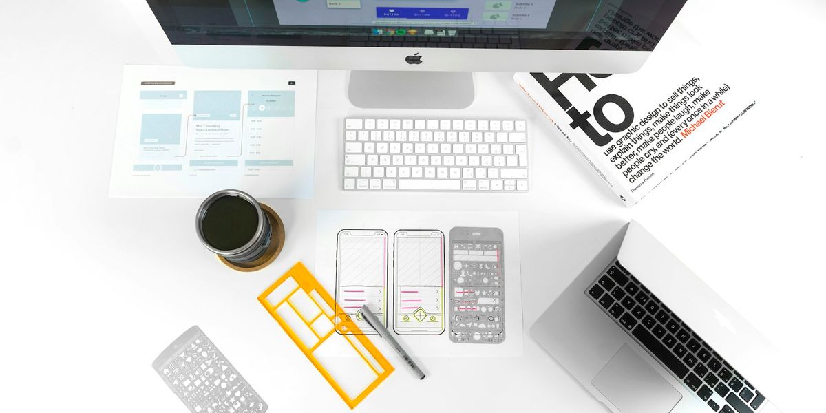 Desk with printed website wireframes, a design stencil and a computer, showing the planning stage of a web development project in Indonesia
