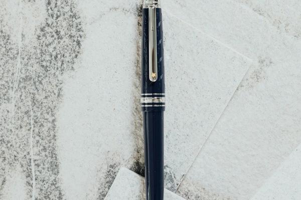 A dark fountain pen lying across sheets of pale paper, the handwritten signature that an electronic signature replaces on a PDF