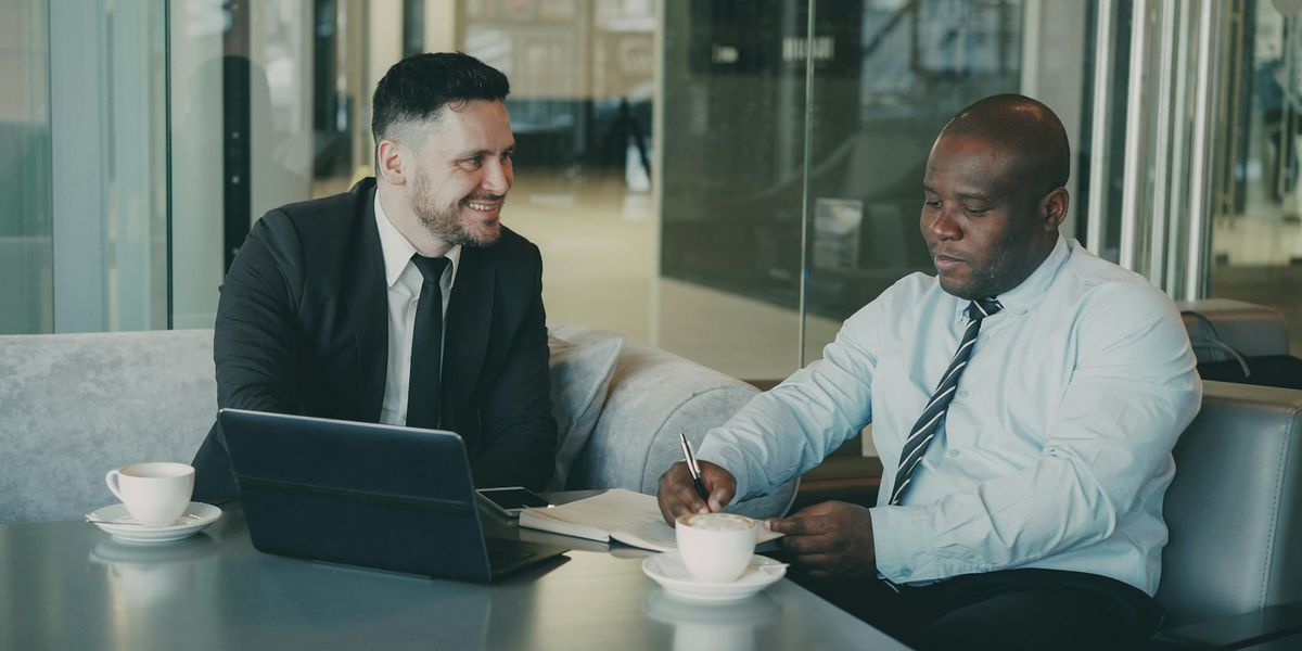 Two colleagues reviewing a printed document and a laptop together at an office table, the kind of contract review that precedes affixing an electronic stamp duty in Indonesia