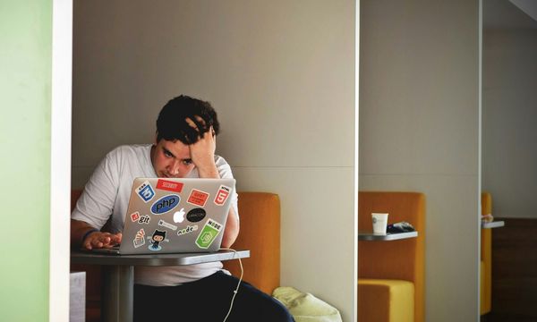 Seseorang menunggu dengan tangan menopang kepala di depan laptop, pengalaman pengunjung ketika website perusahaan lambat dimuat