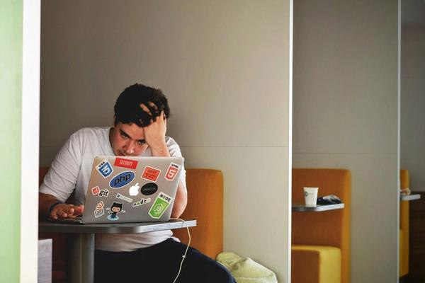 Seseorang menunggu dengan tangan menopang kepala di depan laptop, pengalaman pengunjung ketika website perusahaan lambat dimuat