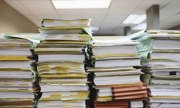 Tumpukan berkas dan map dokumen pelanggan di atas meja kantor, ilustrasi kewajiban perusahaan menurut UU PDP untuk mendata dan melindungi data pribadi