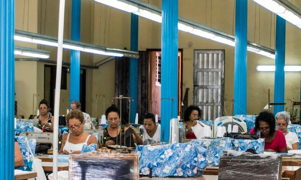 Deretan penjahit mengerjakan potongan kain bermotif sama di lantai konveksi, gambaran aplikasi jadi yang dipakai banyak bisnis sekaligus