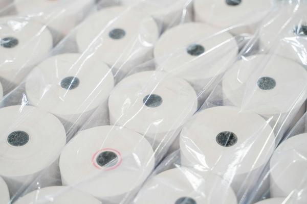 Stacked rolls of blank thermal receipt paper, the manual paperwork that automated invoicing replaces