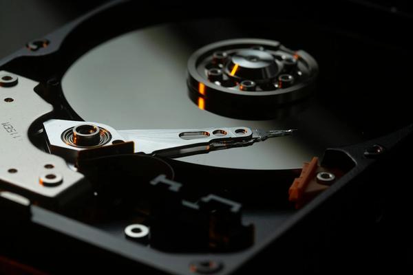 Piringan dan lengan baca hard disk yang terbuka, ilustrasi perangkat fisik yang harus dirawat sendiri saat perusahaan memilih server sendiri dibanding cloud