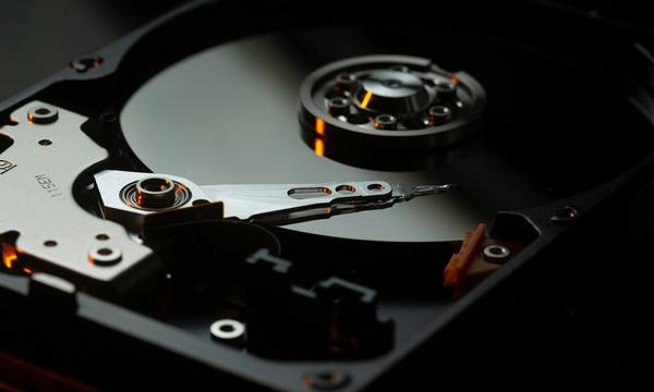 Piringan dan lengan baca hard disk yang terbuka, ilustrasi perangkat fisik yang harus dirawat sendiri saat perusahaan memilih server sendiri dibanding cloud