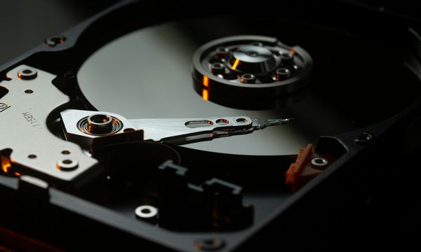 Open hard disk platter and read arm, illustrating the physical hardware a company maintains itself when it chooses an on-premise server over cloud