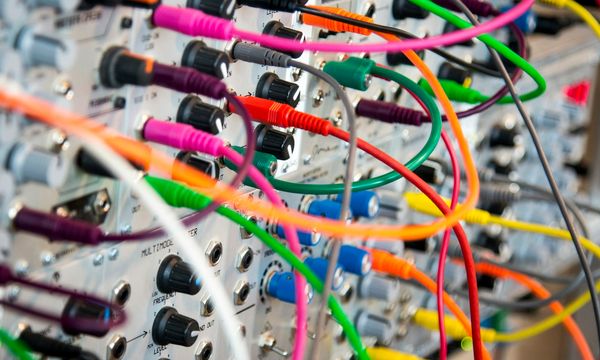 Colour-coded network patch cords plugged into a patch panel in an office equipment rack