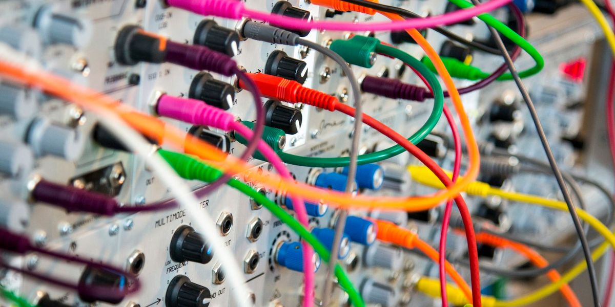 Colour-coded network patch cords plugged into a patch panel in an office equipment rack