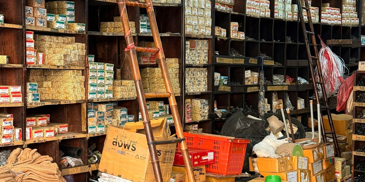 Wall of wooden pigeonhole shelves in a hardware shop packed with small boxes of fasteners and hand-written labels, the kind of stock a POS and an inventory system have to agree on