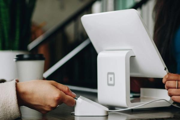 Pelanggan menempelkan kartu ke mesin pembaca di samping tablet kasir di meja toko kecil, contoh langkah digitalisasi UMKM dari nol lewat pembayaran non-tunai