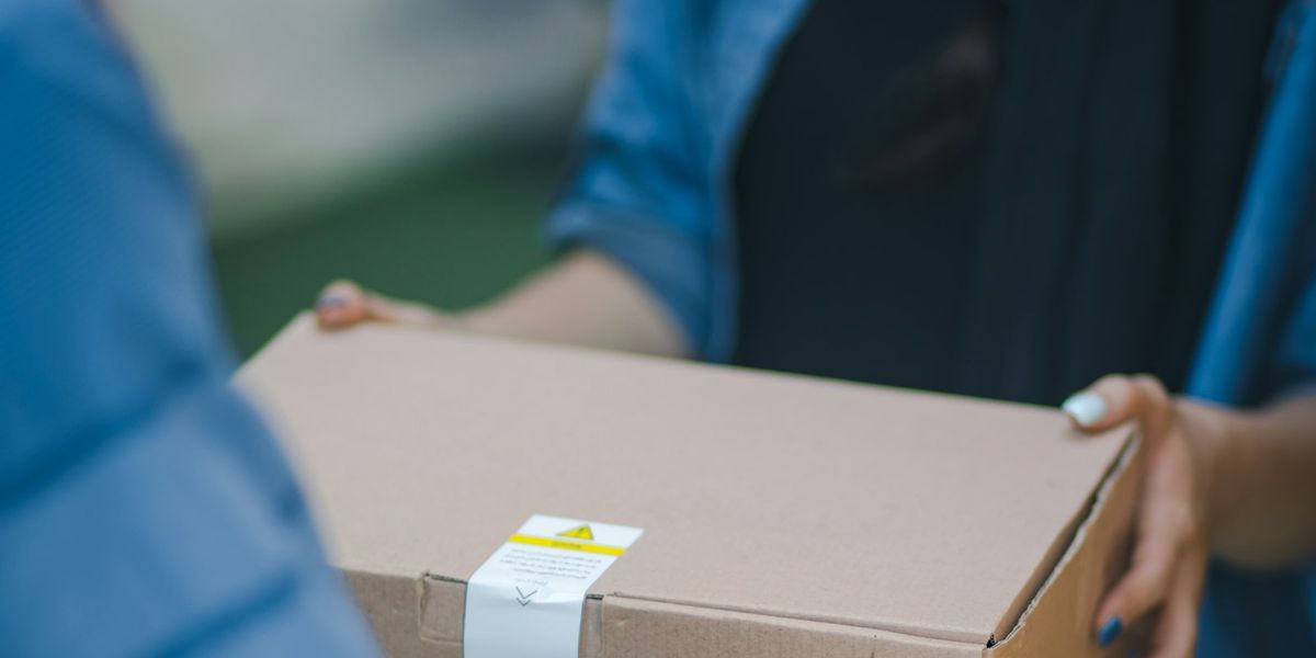 Kurir menyerahkan paket kardus kepada pembeli, gambaran pengiriman order dari toko di website sendiri maupun marketplace