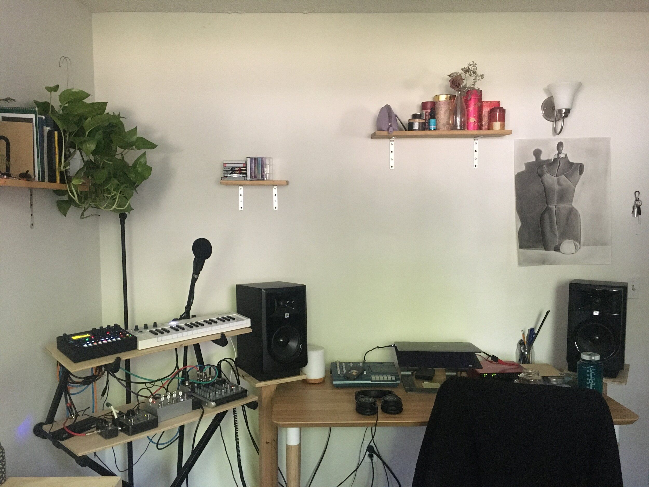 Emma's workspace that contains a few small shelves, some plants, a desktop with studio monitors and other assorted synths and modular equipment.