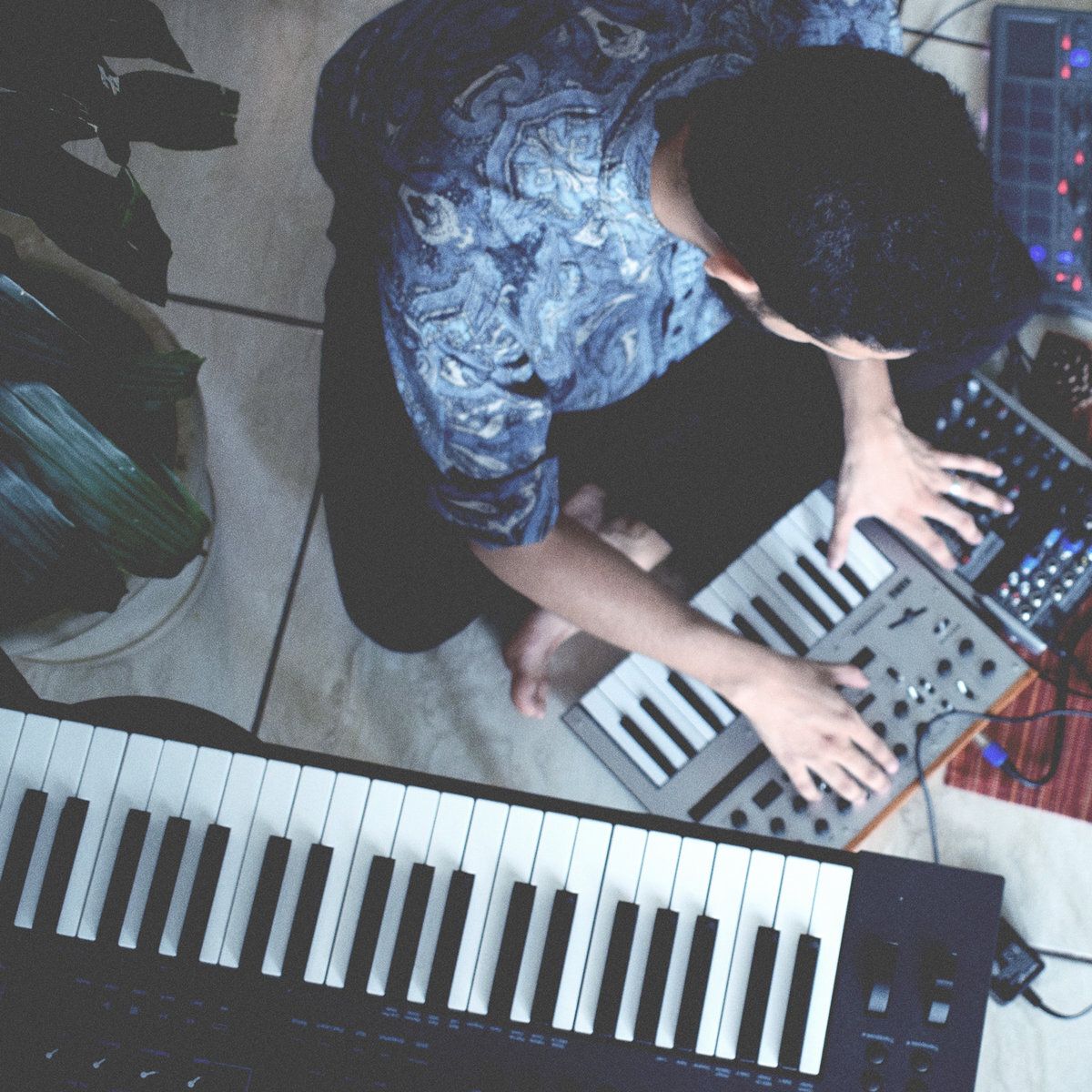 An overhead photo of Wilmer performing in a small room on a couple synthesizers.