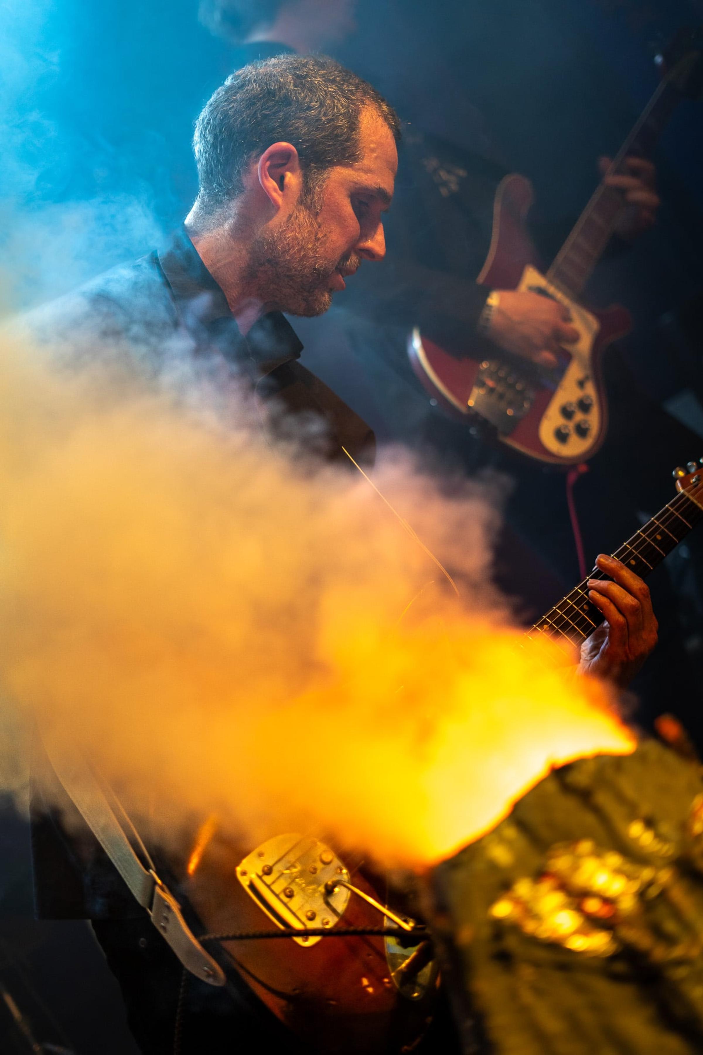 Gitarzysta w pomarańczowym dymie scenicznym
