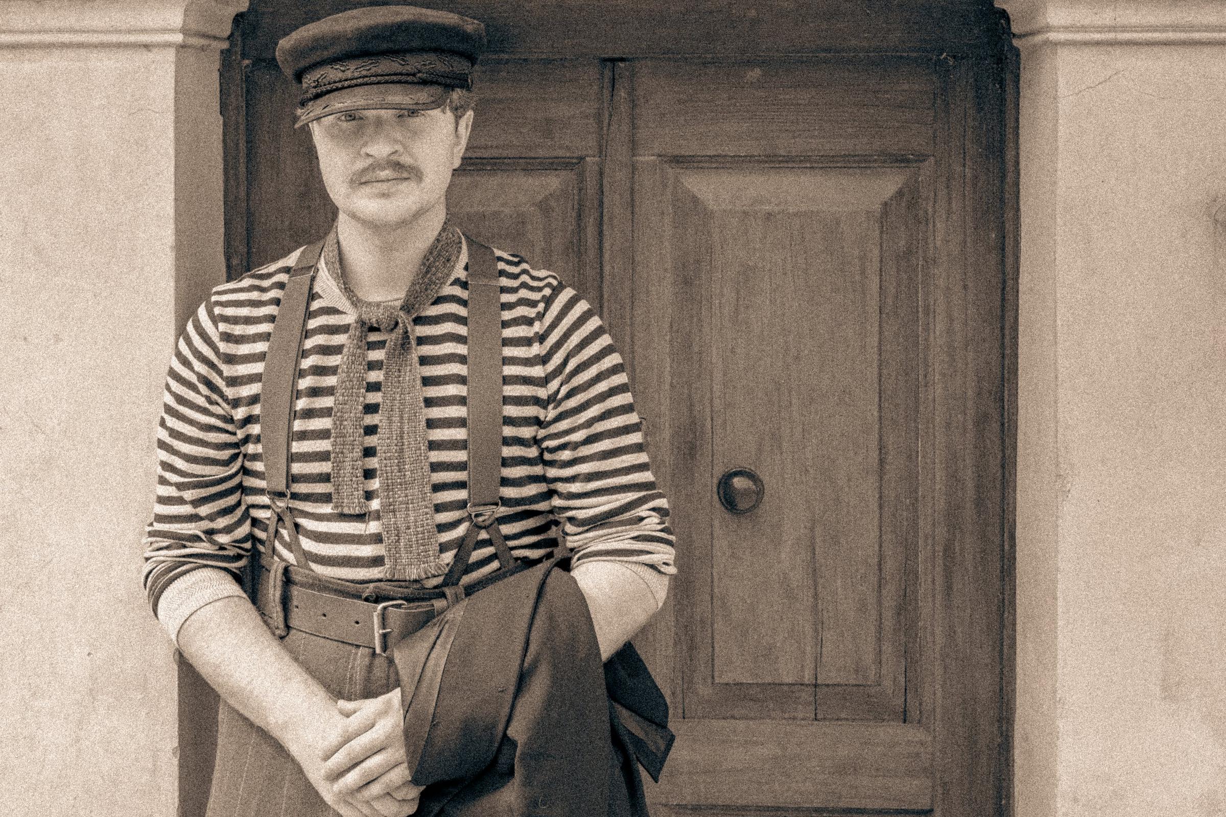 Portret mężczyzny w kaszkiecie na tle drewnianych drzwi, sepia
