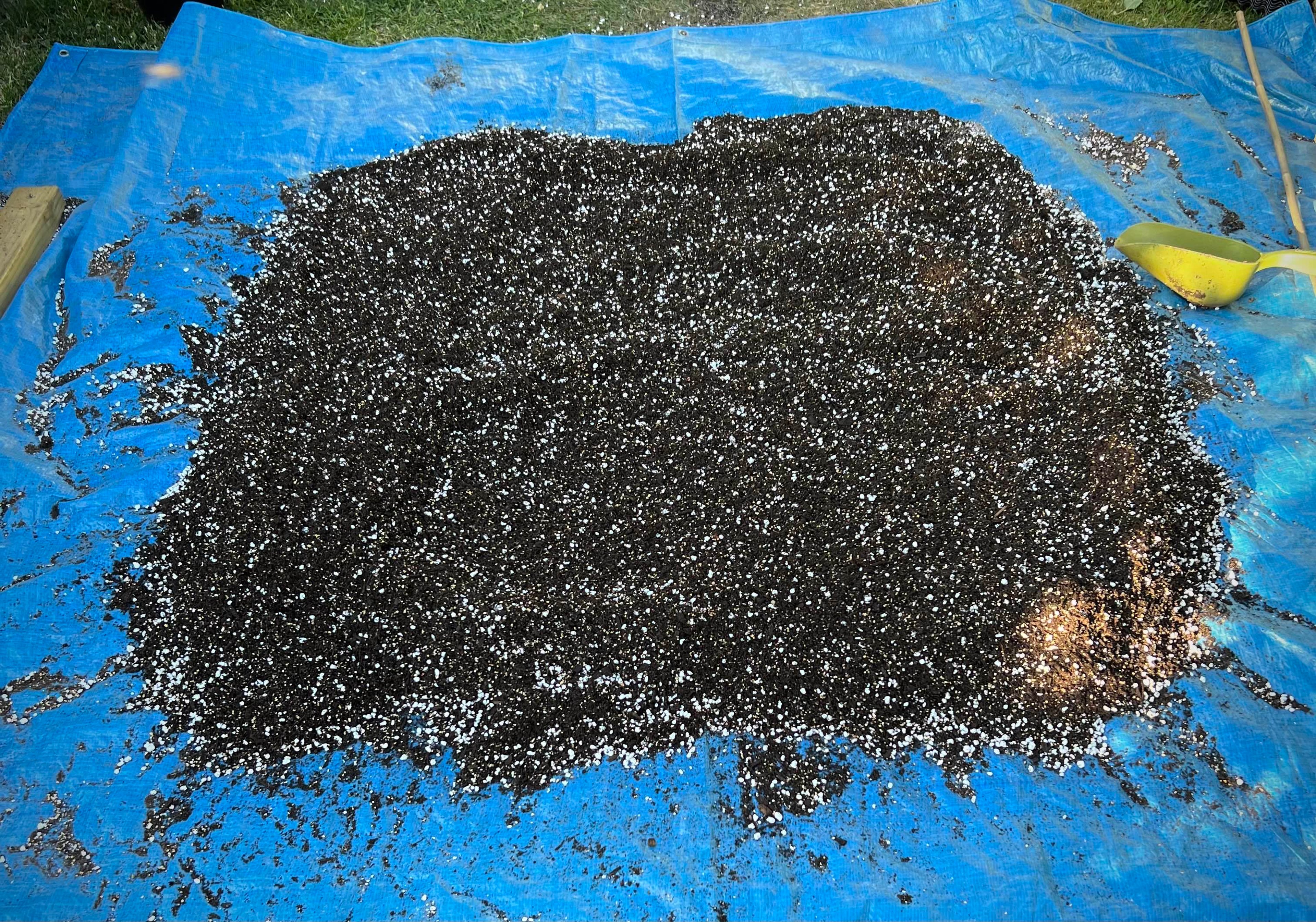 Soil being mixed on top of a blue tarp in the garden.