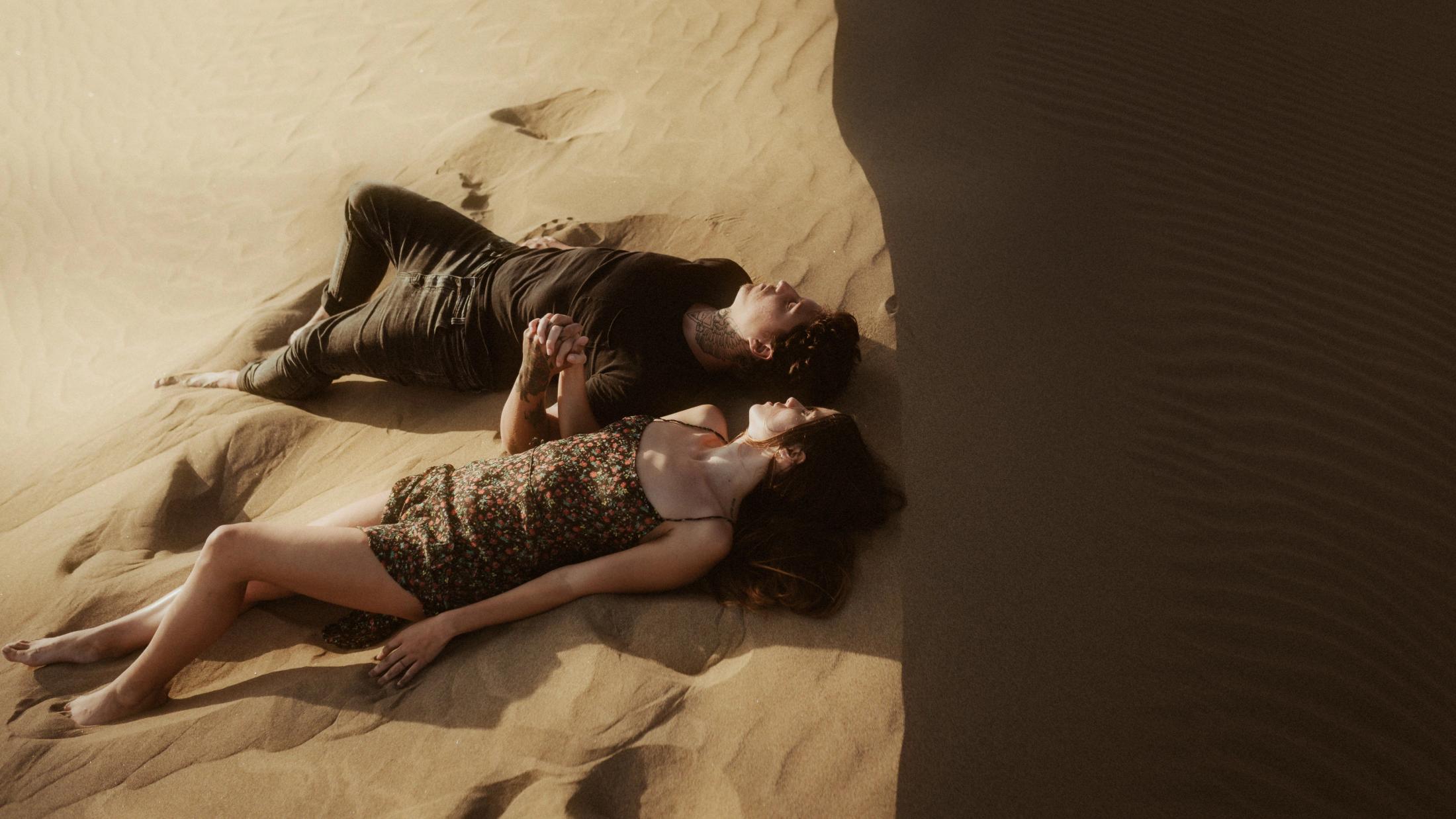 Liegend im Sand, umarmen sie sich.