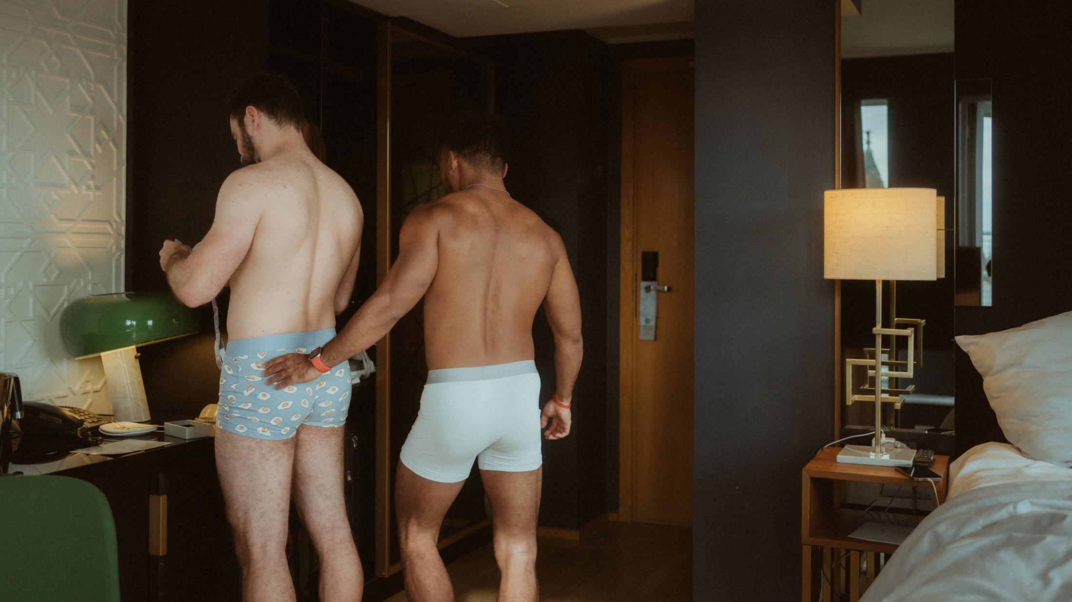Kris rests a hand on Ilya's patterned underwear while they get ready in the hotel room.