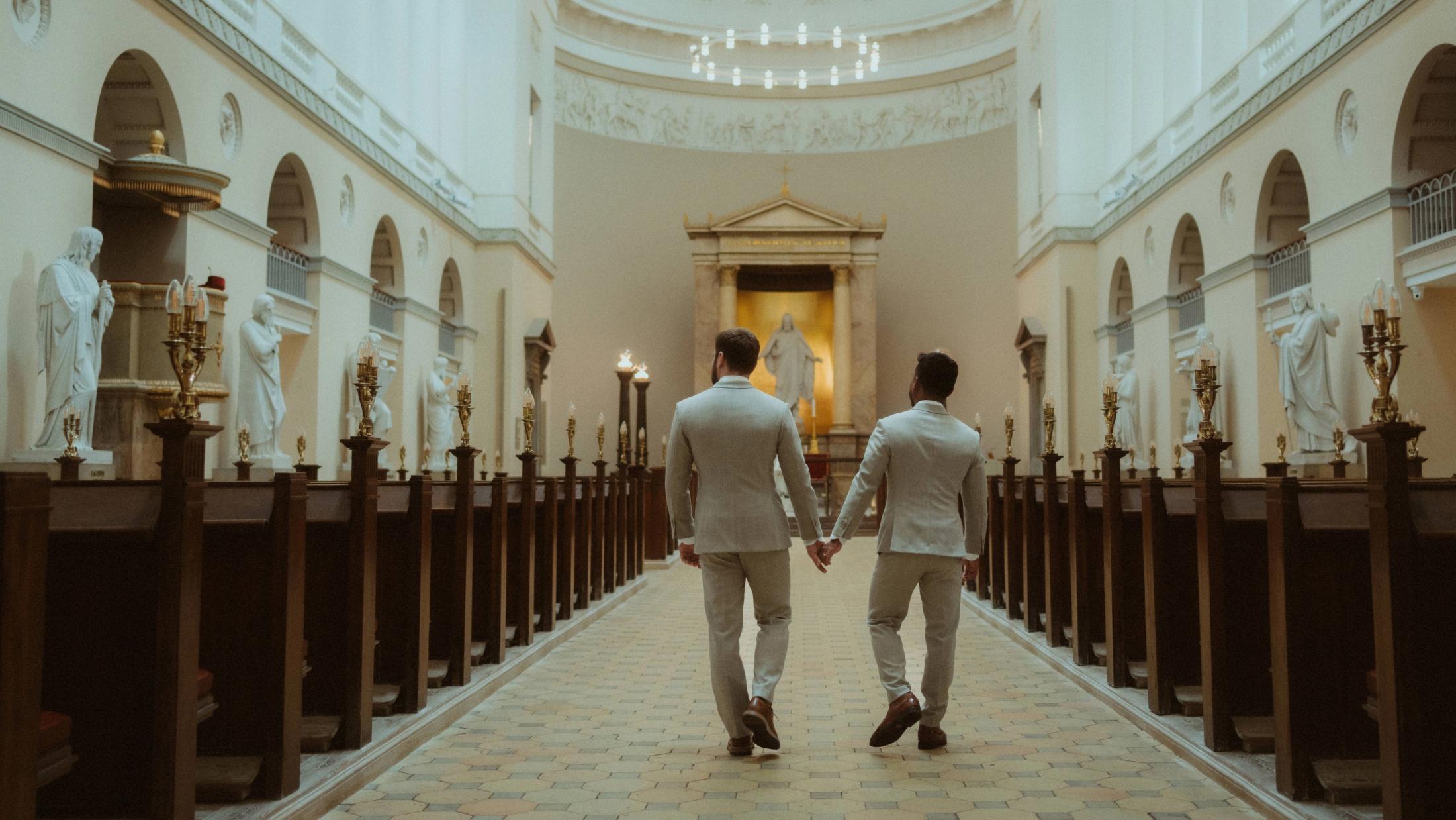 The newly married couple walks away through a long hall inside Copenhagen City Hall.