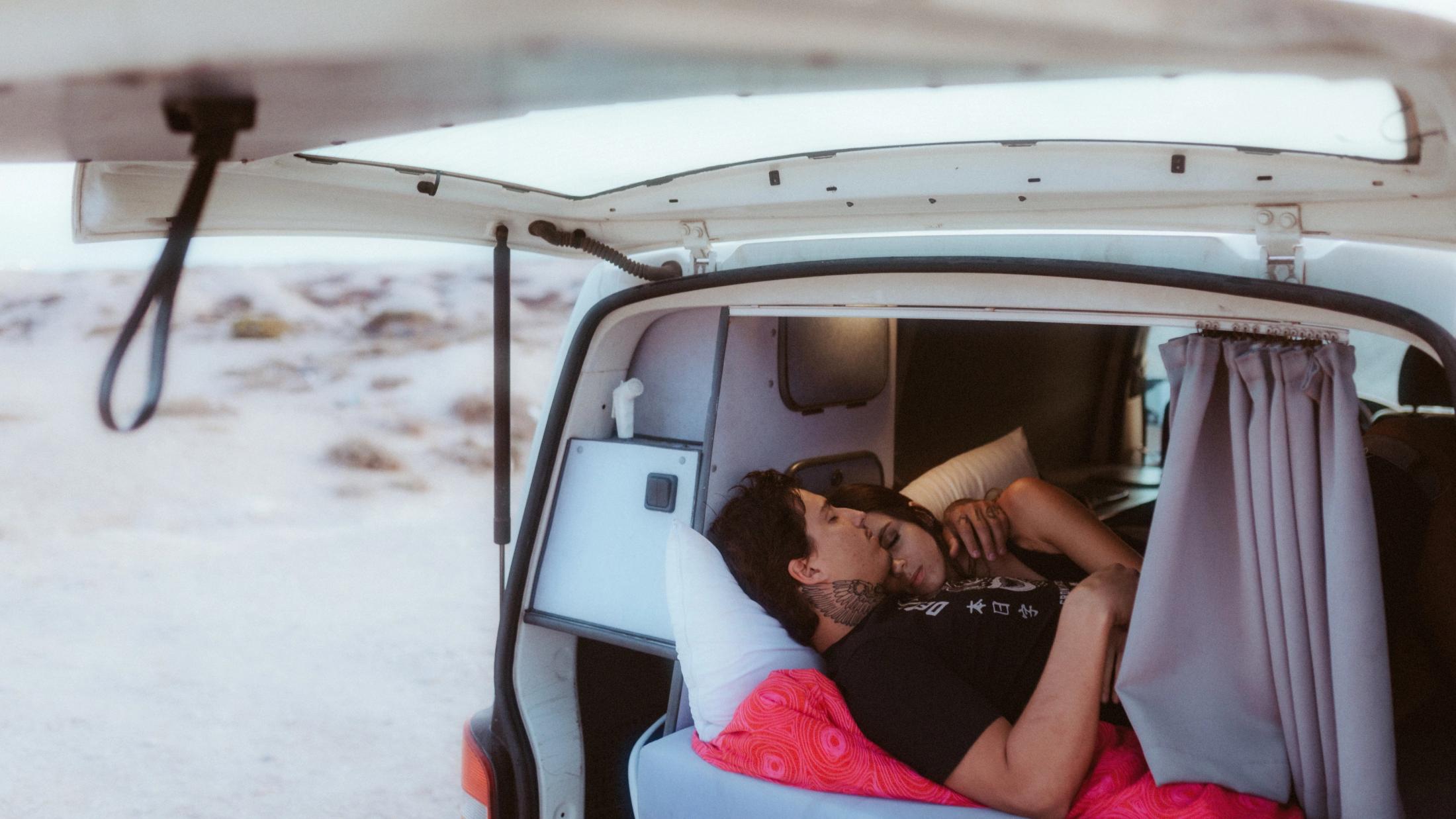 Weitwinkelaufnahme des schlafenden Paares im Campervan.