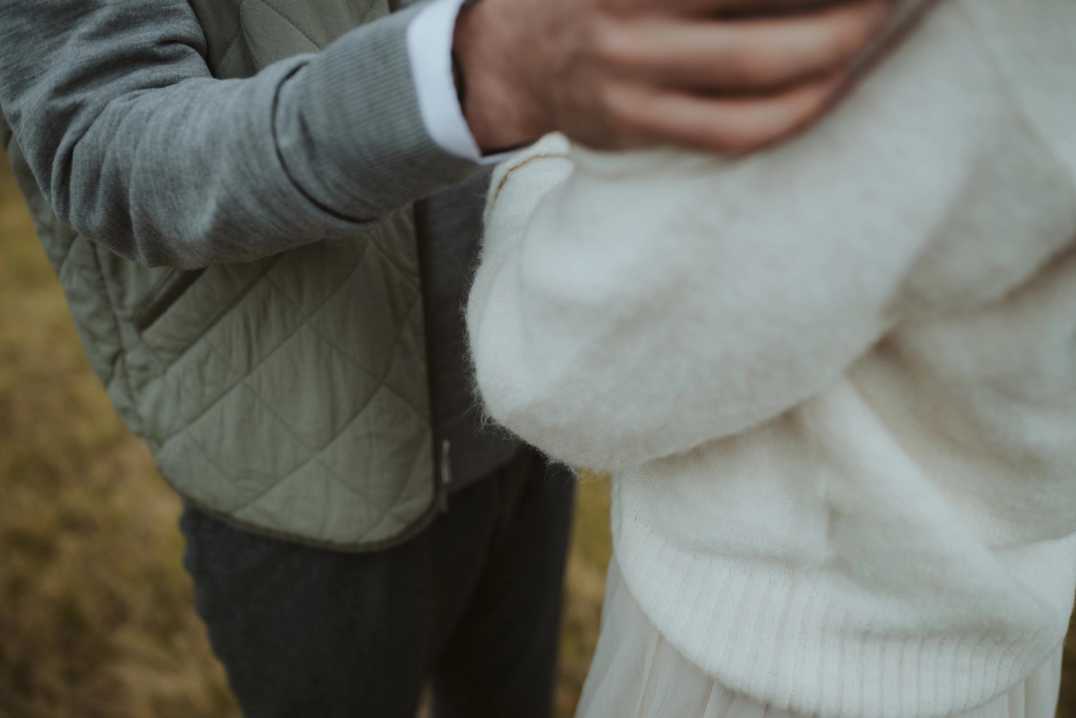 Close detail of hands holding the sleeve of a knitted sweater.
