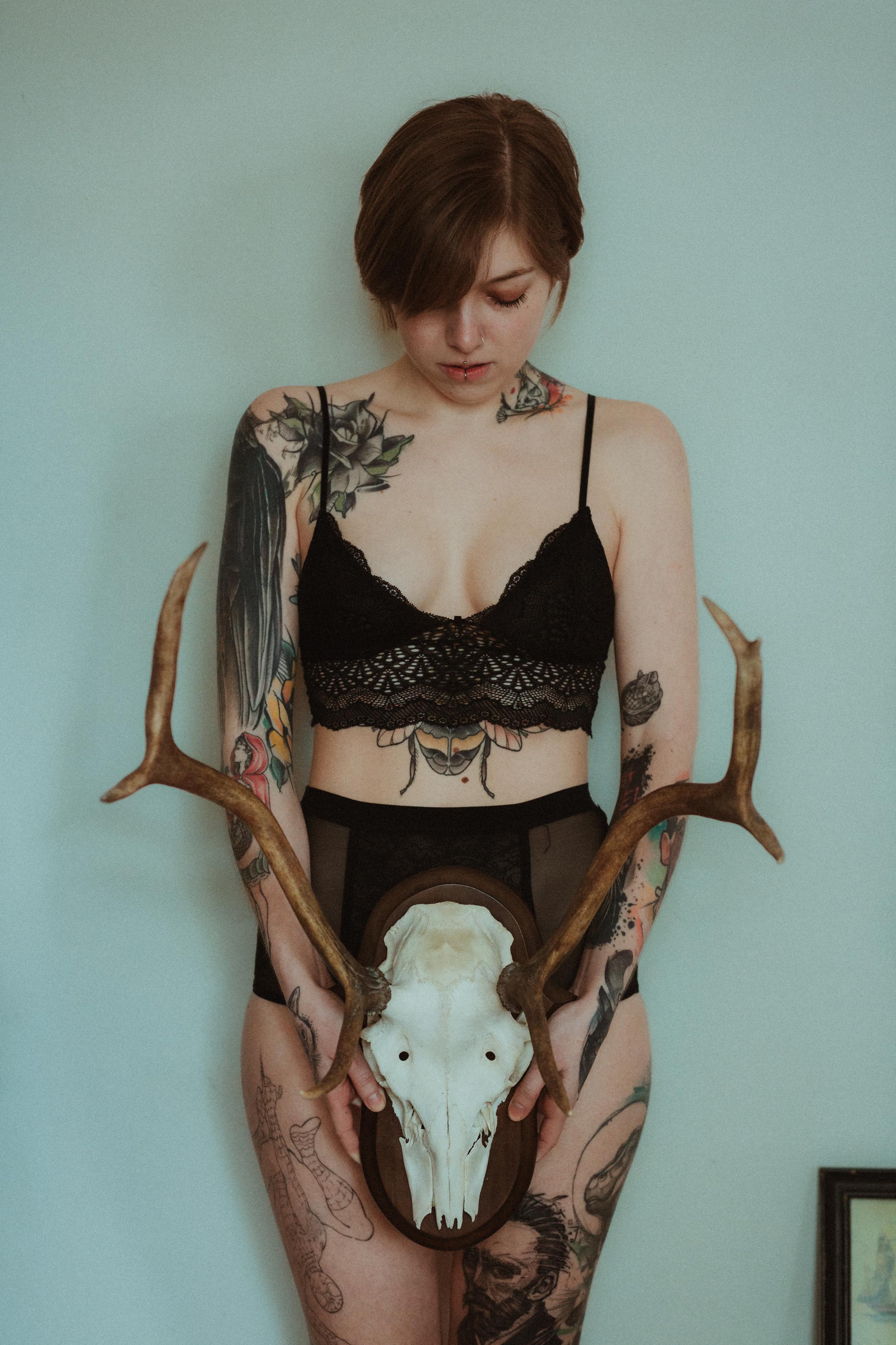 Anki stands holding a deer skull with antlers in front of her body.