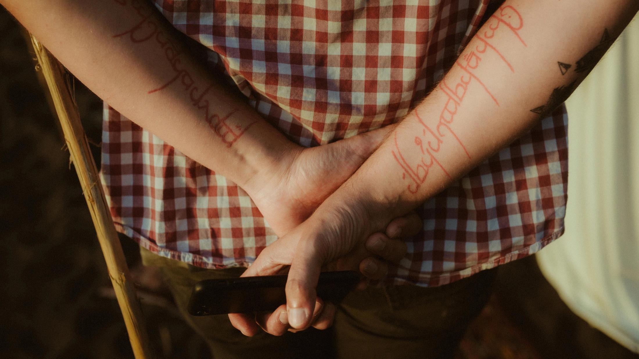 Tattooed forearms and folded hands during the wedding ceremony.