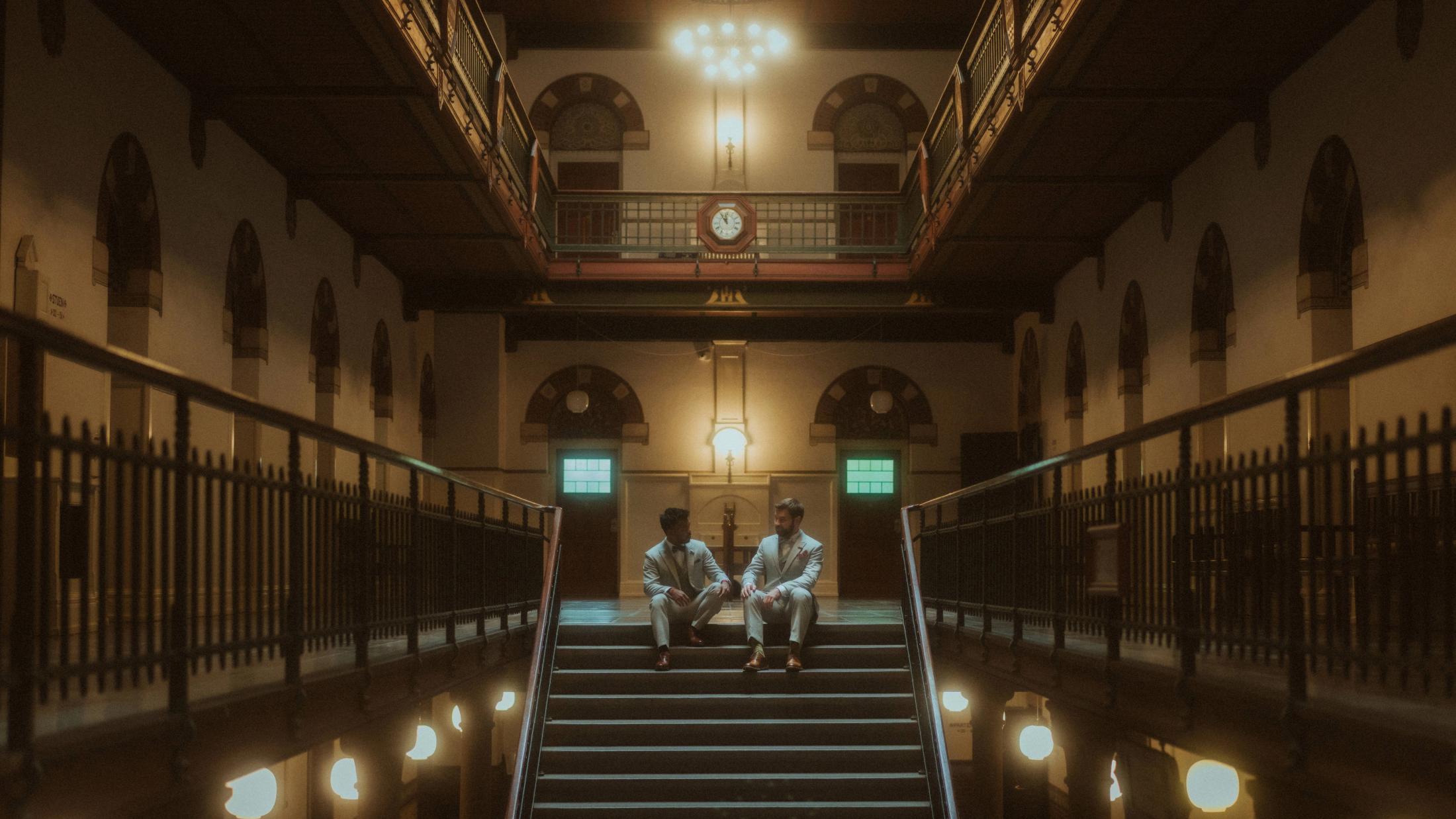 Kris and Ilya sit together at the far end of the grand staircase inside Copenhagen City Hall.